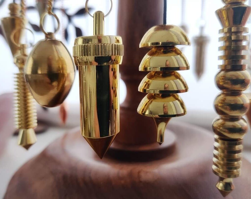 Koperen pendels op achtergrond van houtenstandaard gebruikt bij pendel workshop